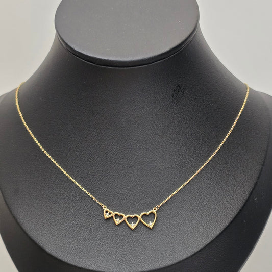A delicate gold chain necklace with three small open heart charms, displayed on a matte black jewelry bust against a light gray background.